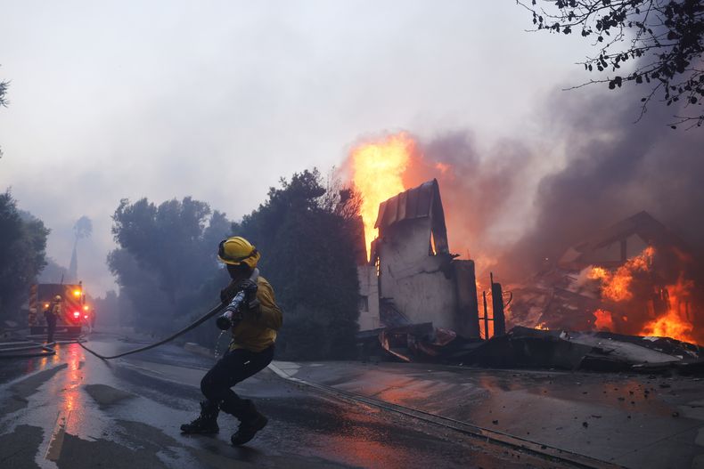 Un bombero intenta contener el avance de un incendio que consume una estructura en Pacific Palisades, el martes 7 de enero de 2025, en Los Ángeles. (AP Foto/Etienne Laurent)