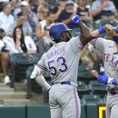 Adolis Garcia (53), de los Rangers de Texas, felicita a Josh Jung en el plato después del cuadrangular frente al abridor de los Medias Blancas de Chicago, Tanner Banks, durante la tercera entrada del juego de béisbol el lunes 19 de junio de 2023, en Chicago. (AP Foto/Charles Rex Arbogast)