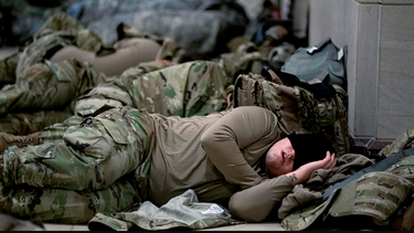 escandalo en washington: enviaron a miembros de la guardia nacional a dormir en el piso de  un estacionamiento de carros