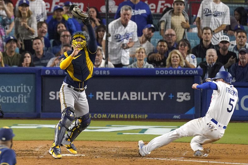 Freddie Freeman, derecha, de los Dodgers de Los Ángeles, anota con un sencillo de Will Smith, mientras el receptor de los Cerveceros de Milwaukee, William Contreras, toma un tiro alto, durante la sexta entrada del juego de béisbol, el miércoles 16 de agosto de 2023, en Los Ángeles. (AP Foto/Mark J. Terrill)