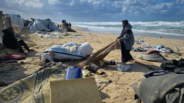 Una mujer jala una alfombra después de que lluvias nocturnas inundaran un campamento de tiendas de campaña junto a la playa, el domingo 28 de diciembre de 2025, en Jan Yunis, en el sur de la Franja de Gaza. (AP Foto/Mohammad Jahjouh)