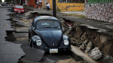 americateve | Un par de autos yacen en una porci&oacute;n de una calle hundida por las intensas lluvias en el puerto de Veracruz, M&eacute;xico, el martes 2 de septiembre de 2014. Los estados del Golfo de M&eacute;xico esperan m&aacute;s lluvias provocadas por la torme