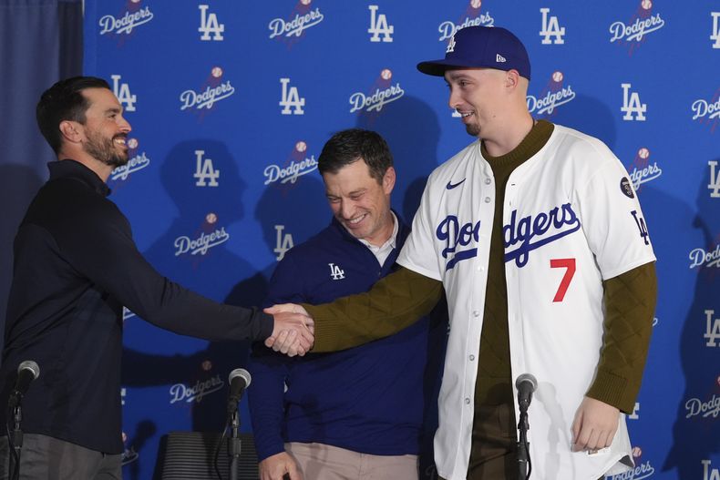 El pitcher de los Dodgers de Los Ángeles Blake Snell le da la mano al gerente general Brandon Gomes tras ser presentado con la camiseta del equipo por el presidente de operaciones Andrew Friedman en conferencia de prensa el martes 3 de diciembre del 2024. (AP Foto/Jae C. Hong)