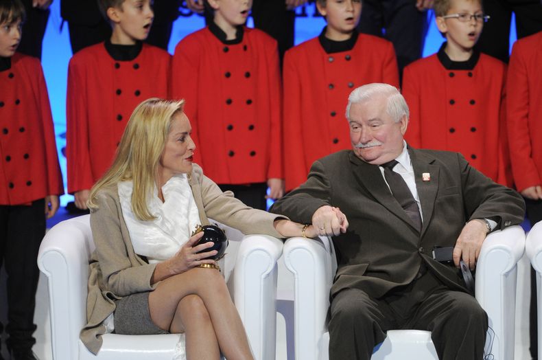 La actriz estadounidense Sharon Stone y el ex presidente polaco Lech Walesa se toman de la mano mientras escuchan un coro infantil en la reuni&oacute;n de Premios Nobel de la Paz en Varsovia, Polonia, el mi&eacute;rcoles 23 de octubre del 2013. (Foto AP/A