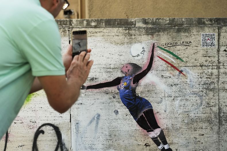 Un sujeto toma una fotografía del grafiti de la artista Laika celebrando a la jugadora de voleibol Paola Egonu después de que fue vandalizado en Roma el miércoles 14 de agosto del 2024. (AP Foto/Gregorio Borgia)