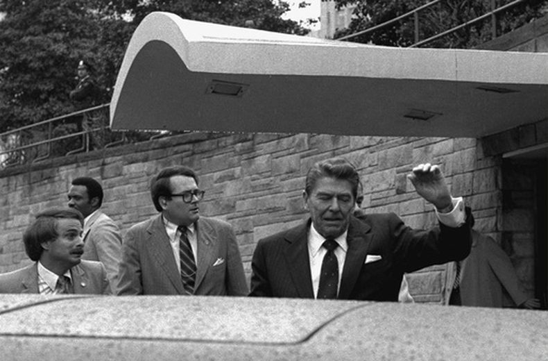ARCHIVO - El presidente Ronald Reagan levanta el brazo izquierdo el día que un hombre le disparó al salir del Hotel Hilton, en Washington, lunes 30 de marzo de 1981. (Foto AP/Ron Edmonds, Archivo)