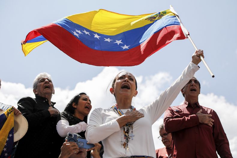 La líder opositora María Corina Machado ondea una bandera nacional venezolana durante una manifestación para protestar por los resultados oficiales que declararon al presidente Nicolás Maduro como ganador de las elecciones presidenciales de julio, en Caracas, Venezuela, el sábado 17 de agosto de 2024. (Foto AP/Cristian Hernández)