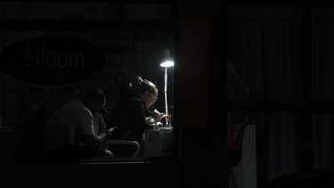 Una mujer hace un trabajo de manicura bajo una lámpara con un foco recargable durante un corte de luz en Quito, Ecuador, el miércoles 11 de diciembre de 2024, ante la crisis energética y el racionamiento eléctrico de varias horas diarias que las autoridades han atribuido a una sequía. El gobierno del presidente Daniel Noboa anunció que los cortes quedarían suspendidos desde el 20 de diciembre durante las fiestas navideñas y de fin de año. (AP Foto/Dolores Ochoa)
