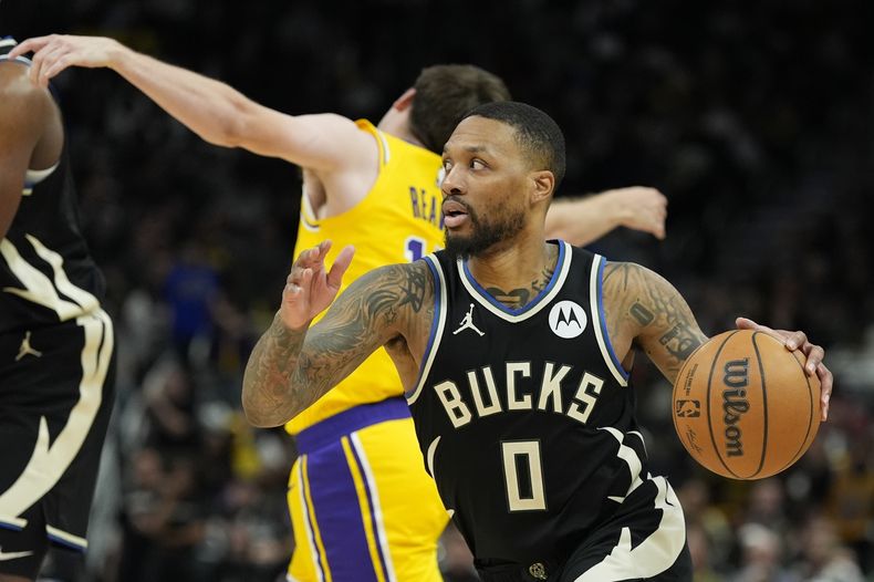 Damian Lillard, de los Bucks de Milwaukee, supera a Austin Reaves, de los Lakers de Los Ángeles, durante la segunda mitad de un partido de baloncesto de la NBA, el martes 26 de marzo de 2024, en Milwaukee. Los Lakers ganaron 128-124 en doble tiempo extra. El escolta de los Bucks de Milwaukee no jugará el martes por la noche contra los Wizards de Washington debido a una distensión en la ingle. (AP Foto/Morry Gash)