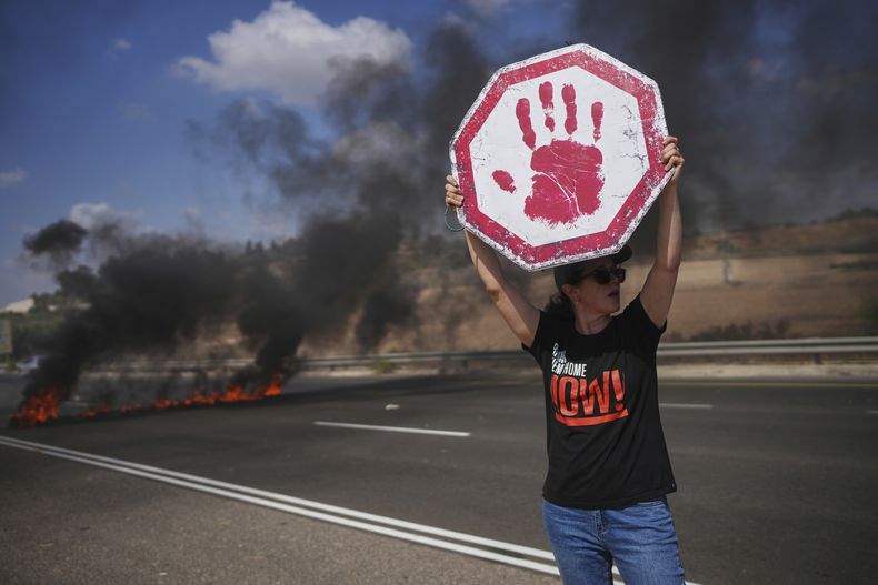 Una manifestante bloquea una carretera durante una protesta para reclamar la liberación de todos los rehenes en poder de Hamás y pedir el final de la guerra en la Franja de Gaza, en Modiin, Israel, el martes 26 de agosto de 2025. (AP Foto/Ohad Zwigenberg)