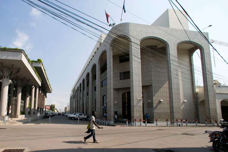ARCHIVO - Un peatón camina cerca del Banco de la República de Haití, a la derecha, el jueves 21 de marzo de 2019, en Puerto Príncipe, Haití. (AP Foto/Dieu Nalio Chery, archivo)