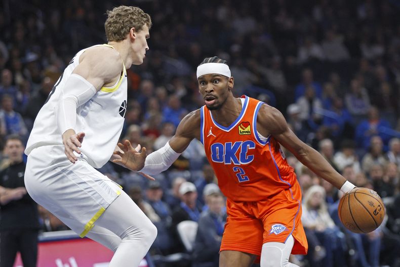 El base de los Thunder de Oklahoma City Shai Gilgeous-Alexander avanza hacia la canasta frente al alero del Jazz de Utah Lauri Markkanen en el encuentro del martes 3 de diciembre del 2024. (AP Foto/Nate Billings)