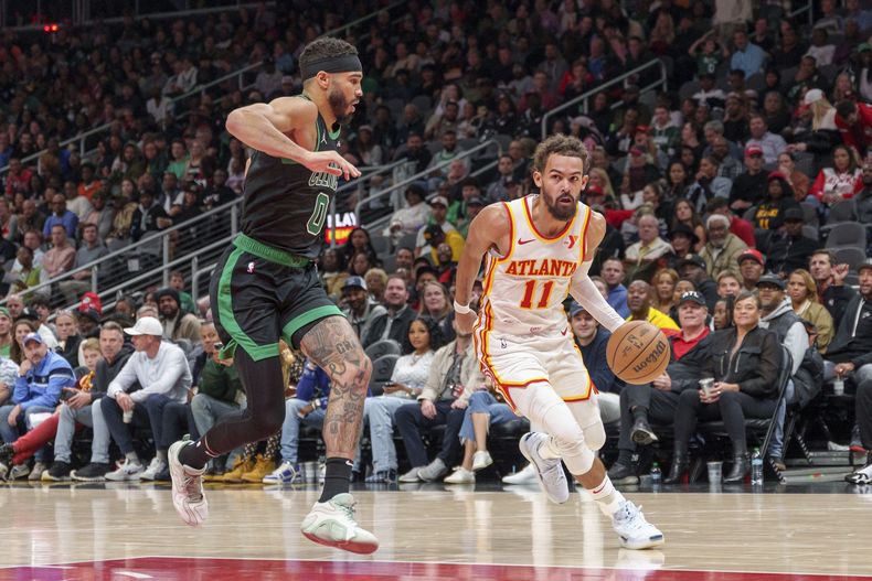 El escolta de los Hawks de Atlanta, Trae Young (11), conduce por el carril mientras es custodiado por el alero de los Celtics de Boston, Jayson Tatum (0), durante la primera mitad de un partido el lunes 4 de noviembre de 2024, en Atlanta. (AP Foto/Jason Allen)