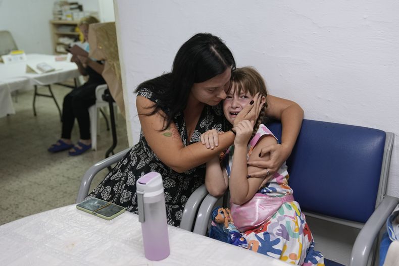 Israelíes se ponen a cubierto en un refugio mientras las sirenas antiaéreas advierten de proyectiles disparados desde la Ciudad de Gaza, en Ashkelon, Israel, el 10 de octubre de 2023. (AP Foto/Ohad Zwigenberg)