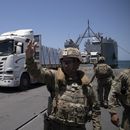 Un soldado del ejército de Estados Unidos hace señas al conductor de un camión cargado con asistencia humanitaria a su llegada al muelle flotante Trident, construido por Estados Unidos, antes de llegar a la playa en la costa de la Franja de Gaza, el martes 25 de junio de 2024. (AP Foto/Leo Correa)