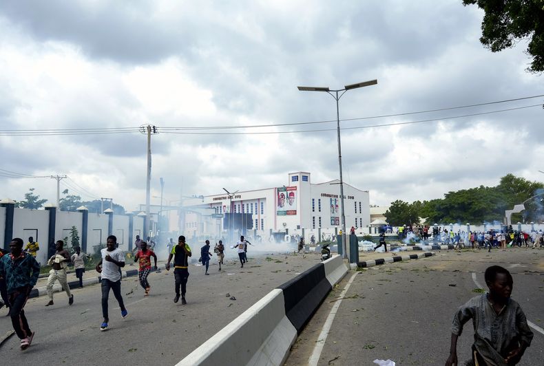 ARCHIVO - Varias personas huyen de los gases lacrimógenos durante una protesta en la calle en Kano, Nigeria, 1 de agosto de 2024. (AP Foto/Sani Maikatanga, Archivo)