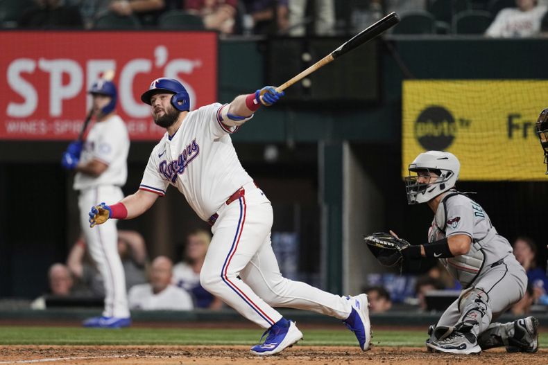 El primera base de los Rangers de Texas Jake Burger da seguimiento a su sencillo anotador frente al catcher de los Diamondbacks de Arizona Adrian del Castillo en la décima entrada el lunes 11 de agosto del 2025. (AP Foto/Tony Gutierrez)