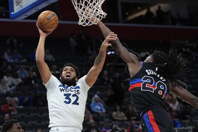 Karl-Anthony Towns, pívot de los Timberwolves de Minnesota, salta hacia la cesta frente a Isaiah Stewart, de los Pistons de Detroit, el miércoles 17 de enero de 2024 (AP Foto/Paul Sancya)
