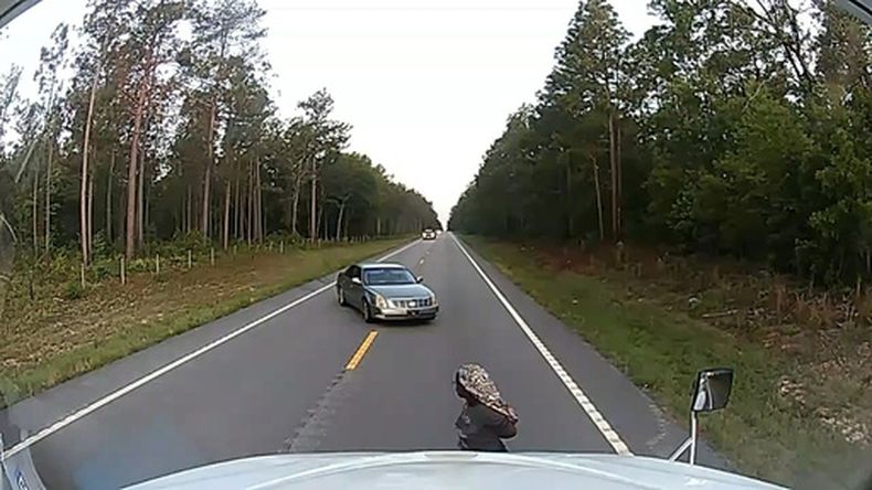 En esta imagen extraída de un video grabado con la cámara de un tablero de camión, se ve a una mujer esposada huyendo de su presunto secuestrador cerca de Aiken, Carolina del Sur, el viernes 29 de mayo de 2026. (Anthony J. Moore vía AP)