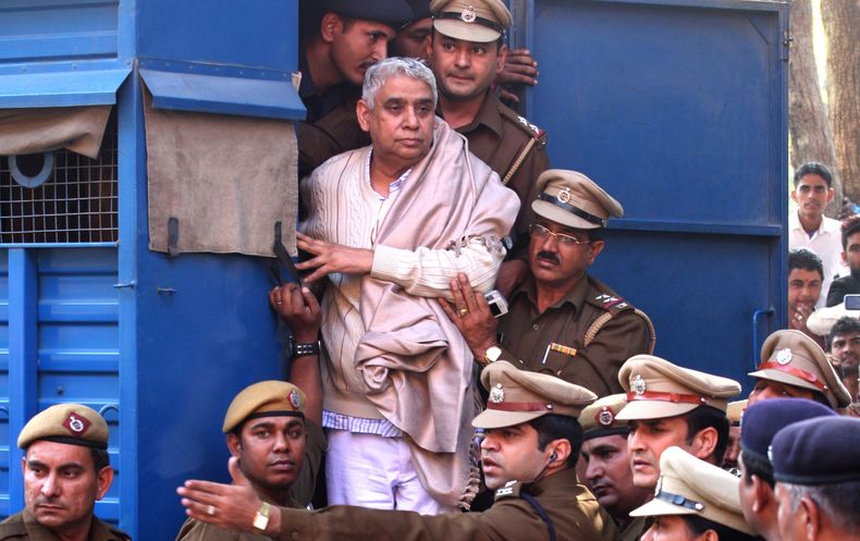 En la imagen, el controvertido gur&uacute; Rampal de pie en la puerta de un veh&iacute;culo policial mientras es trasladado a un tribunal, rodeado por agentes de la polic&iacute;a en Chandigarh, India, el 20 de noviembre de 2014. (Foto AP/Kapil Sethi)