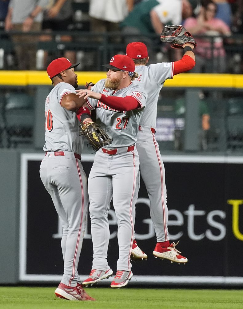 El jardinero izquierdo de los Rojos de Cincinnati, Will Benson, a la izquierda, celebra con el jardinero derecho Jake Fraley y el jardinero central TJ Friedl, detrás, después de la victoria del equipo en un juego de béisbol contra los Rockies de Colorado el martes 4 de junio de 2024, en Denver. (AP Foto/David Zalubowski)