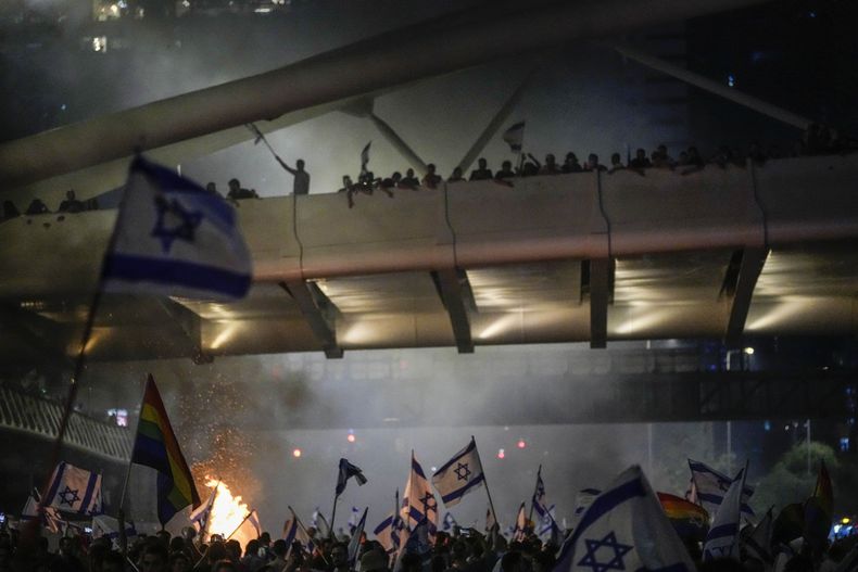 Una hoguera arde mientras israelíes ocupan la autopista Ayalon para protestar contra la propuesta de reforma del sistema judicial del gobierno del primer ministro, Benjamin Netanyahu, en Tel Aviv, el 20 de julio de 2023. (AP Foto/Ariel Schalit)