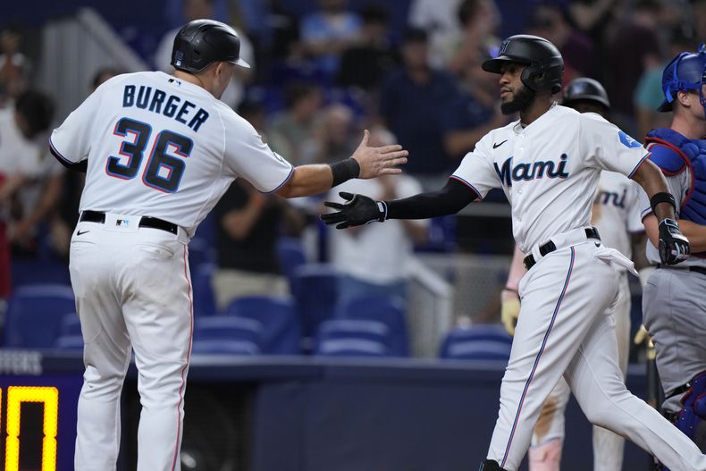 Jake Burger, de los Marlins de Miami, felicita a su compañero Bryan de la Cruz, quien lo empujó con un jonrón en el juego del martes 5 de septiembre de 2023, ante los Dodgers de Los Ángeles (AP Foto/Wilfredo Lee)