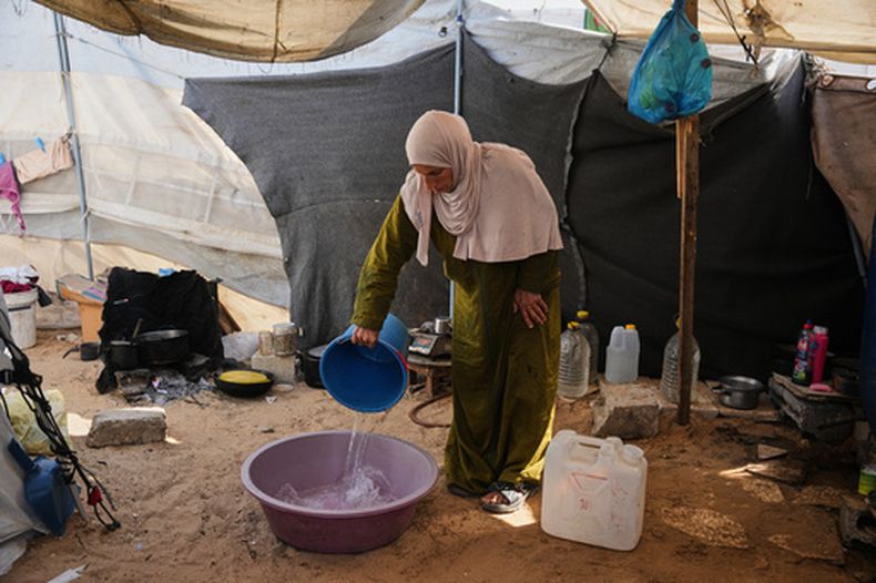 La palestina desplazada Reem Abu Lahia lava su ropa dentro de la tienda donde vive en Jan Yunis, en el sur de la Franja de Gaza, el jueves 30 de abril de 2026. (AP Foto/Abdel Kareem Hana)
