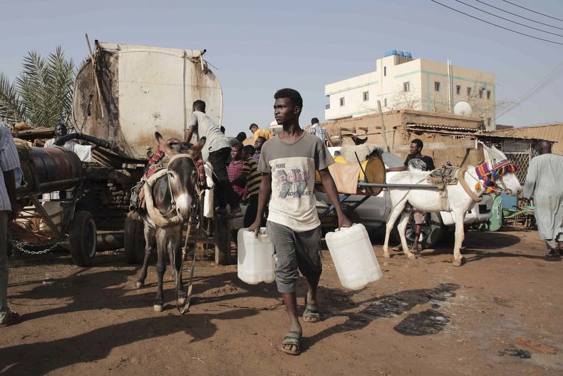 ARCHIVO - Varias personas se reúnen para recoger agua en Jartum, Sudán, el 28 de mayo de 2023, durante una tregua de una semana auspiciada por Estados Unidos y Arabia Saudí. (Foto AP/Marwan Ali)