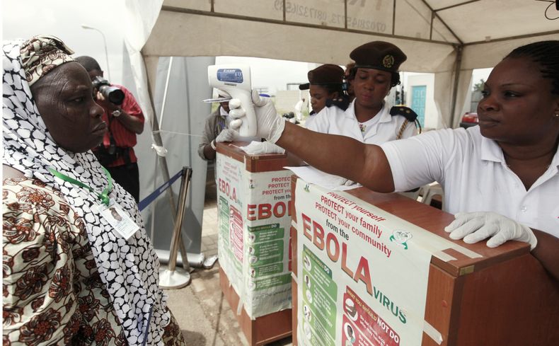 En esta imagen del 18 de septiembre de 2014, una trabajadora nigeriana de salud usa un term&oacute;metro para tomarle la temperatura a una peregrina musulmana antes de abordar un avi&oacute;n rumbo a Arabia Saud&iacute; para la peregrinaci&oacute;n anual,