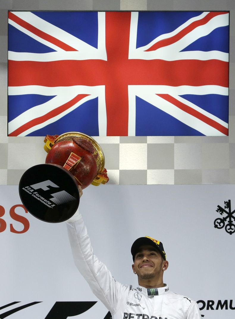 El brit&aacute;nico Lewis Hamilton, de Mercedes, levanta en el podio el trofeo de ganador de la carrera del Gran Premio de Formula Uno en el Circuito Internacional de Shanghai, el domingo 20 de abril de 2014. (AP Foto/Alexander F. Yuan)