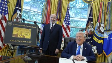 El presidente Donald Trump acompañado del secretario de Comercio, Howard Lutnick, quien se encuentra de pie a un costado de un cartel de la Tarjeta Dorada Trump en el Despacho Oval de la Casa Blanca, el viernes 19 de septiembre de 2025, en Washington. (AP Foto/Alex Brandon)