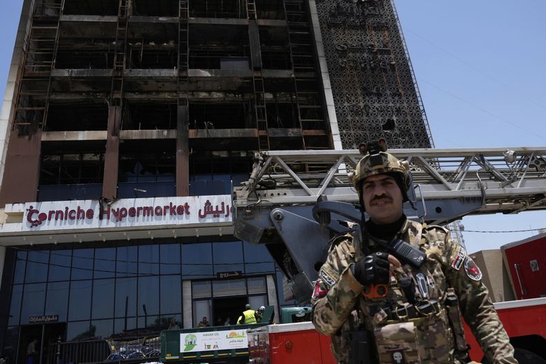 Un guarda de seguridad iraquí hace guardia delante del edificio de un hipermercado incendiado, en Kut, Irak, el 17 de julio de 2025. (AP Foto/Hadi Mizban)