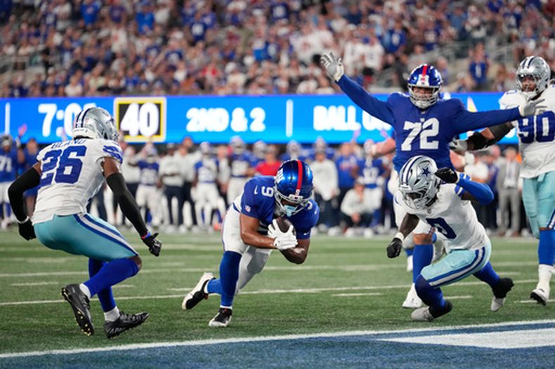 Isaiah Likely (9), ala cerrada de los Giants de Nueva York, consigue una anotación mientas su compañero Jermaine Eluemunor (72) celebra, con Daron Bland (26) y DeMarvion Overshown (0), de los Cowboys de Dallas, sin oportunidad de evitarlo durante la segunda mitad del partido de la NFL, el domingo 13 de septiembre de 2026, en East Rutherford, Nueva Jersey. (AP Foto/Yuki Iwamura)