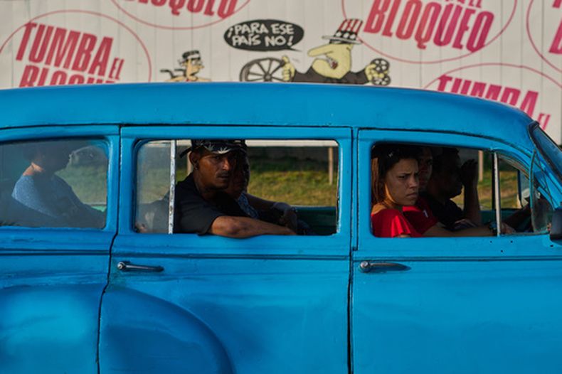 Personas en un taxi frente a un cartel contra el bloqueo estadounidense de Cuba, en La Habana, el 28 de abril del 2026. (AP Foto/Ramón Espinosa)
