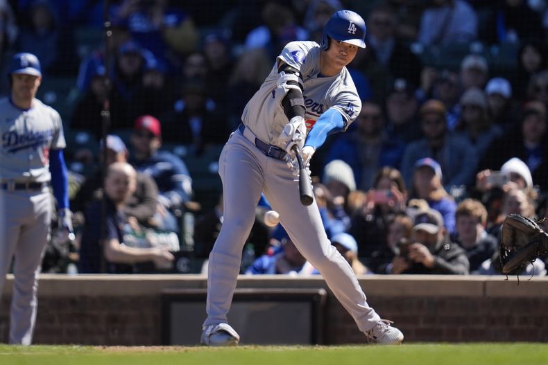 Shohei Ohtani, de los Dodgers de Los Ángeles, batea la pelota, pero el lanzador de los Cachorros de Chicago, Kyle Hendricks, marca el out forzado en primera durante la tercera entrada de un juego de béisbol el viernes 5 de abril de 2024, en Chicago. (AP Foto/Erin Hooley)