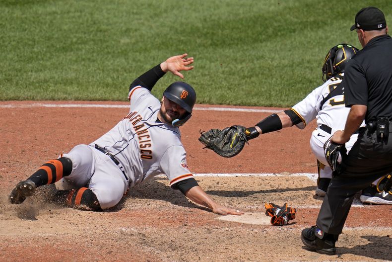 J.D. Davis de los Gigantes de San Francisco se desliza para anotar una carrera ante los Piratas de Pittsburgh, el domingo 16 de julio de 2023. (AP Foto/Gene J. Puskar)