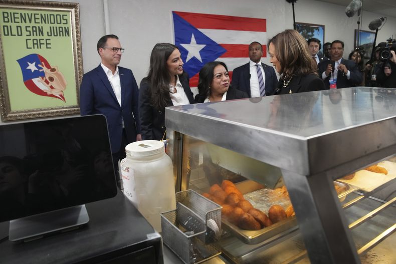 La vicepresidenta y candidata demócrata Kamala Harris, desde la derecha, visita el restaurante Old San Juan Cafe junto a la dueña Diana de La Rosa, la representante de Nueva York Alexandria Ocasio-Cortez, y el gobernador de Pensilvania Josh Shapiro en una visita de campaña a Reading, Pensilvania, el lunes 4 de noviembre de 2024. (AP Foto/Jacquelyn Martin)