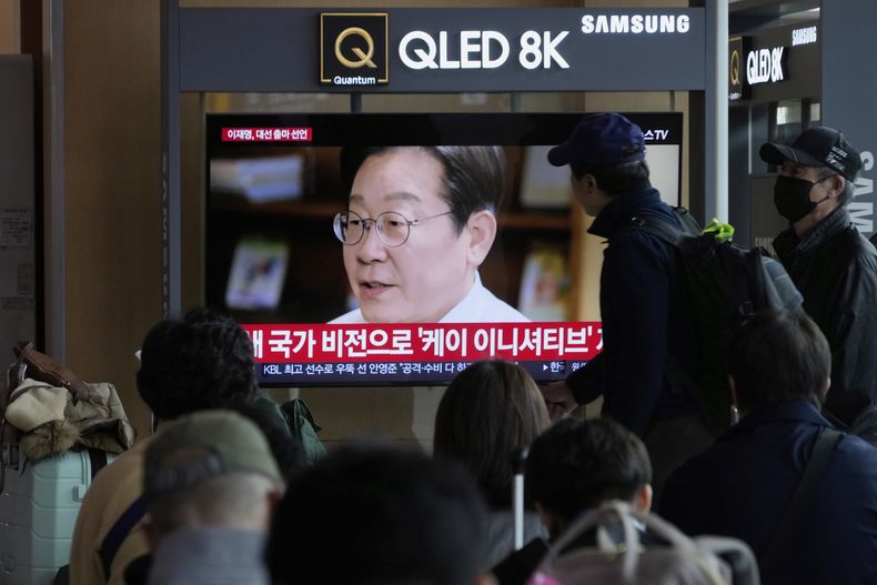 Gente mirando una televisora que muestra al exdirigente del principal partido opositor surcoreano, el Partido Democrático, Lee Jae-myung, anunciando su campaña presidencial en un mensaje en video en la Estación de Ferrocarril de Seúl, Corea del Sur, el jueves 10 de abril de 2025. (AP Foto/Ahn Young-joon)