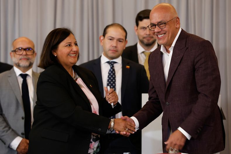 Dinorah Figuera, representante de la oposición venezolana, izquierda, y el presidente de la Asamblea Nacional, Jorge Rodríguez, se estrechan la mano tras firmar acuerdos al finalizar la segunda ronda de conversaciones políticas, el viernes 25 de septiembre de 2026, en Caracas, Venezuela. (AP Foto/Pedro Mattey)