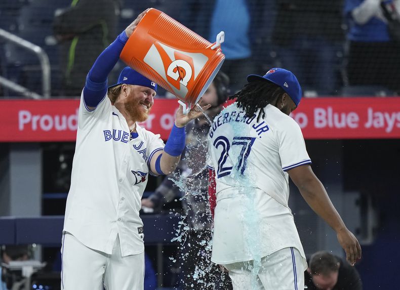 Justin Turner, de los Azulejos de Toronto, vacía la hielera encima del dominicano Vladimir Guerrero Jr., tras la victoria sobre los Yankees de Nueva York, el martes 16 de abril de 2024 (Nathan Denette/The Canadian Press via AP)