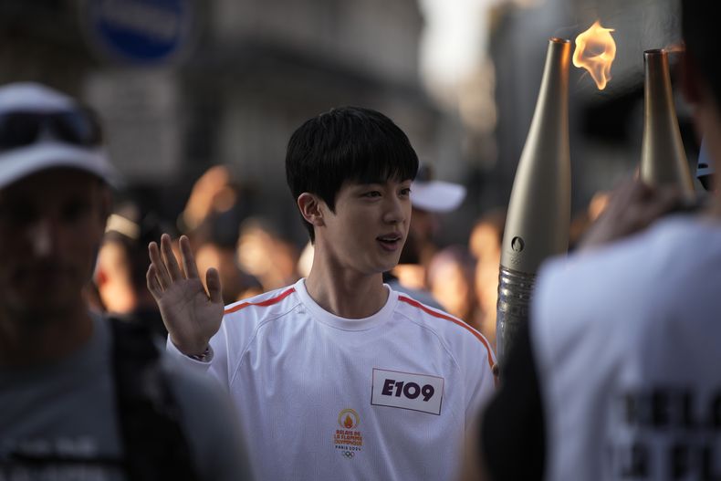 Jin, el miembro más antiguo del grupo de K-pop BTS, toma la antorcha olímpica, el domingo 14 de julio de 2024 en París. Jin llevó la antorcha olímpica en el área del Museo del Louvre de París después de completar recientemente su servicio militar obligatorio. (AP Foto/Louise Delmotte)