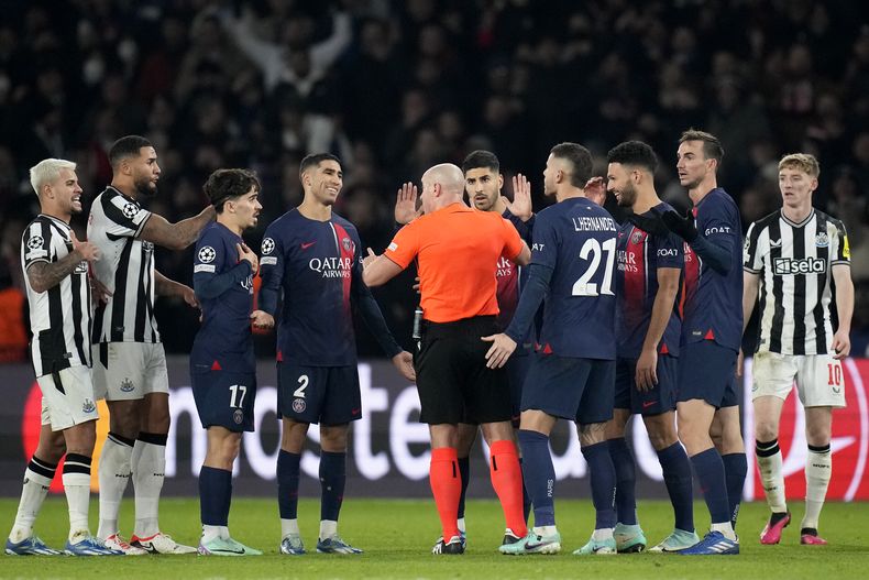Los jugadores del PSG rodean al árbitro Szymon Marciniak al reclamar un penal en el partido contra Newcastle en la Liga de Campeones, el martes 28 de noviembre de 2023, en París. (AP Foto/Christophe Ena)