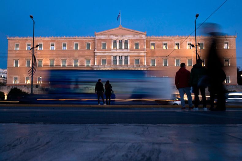 ARCHIVO - Varias personas, delante del Parlamento de Grecia, mientras los autos circulan por el centro de Atenas, el 21 de noviembre de 2017. (AP Foto/Petros Giannakouris, archivo)