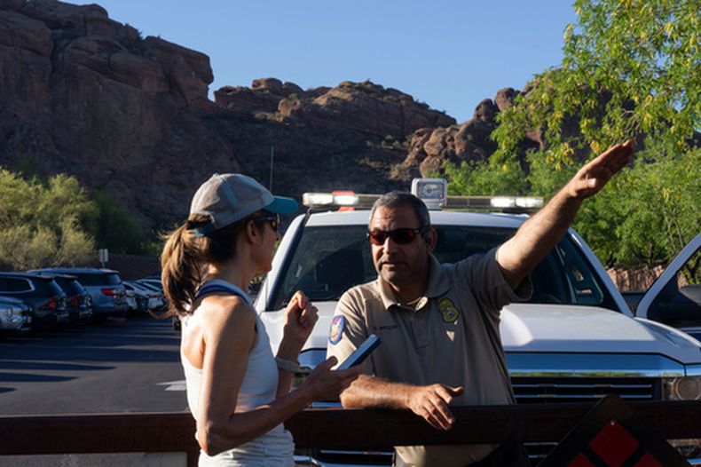 Un guardaparques le da instrucciones a una excursionista debido al calor extremo en Camelback Mountain, en Phoenix, el 19 de marzo del 2026. (AP foto/Rebecca Noble)