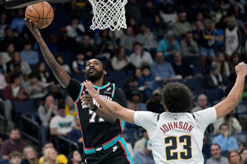El base de los Grizzlies de Memphis DeJon Jarreau salta con el balón para anotar frente al alero de los Nuggets de Denver Cameron Johnson el miércoles 18 de marzo del 2026. (AP Foto/Brandon Dill)
