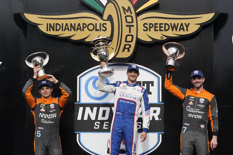 El español Alex Palou, al centro, sostiene el trofeo tras ganar el Gran Premio de Indianápolis d la IndyCar, junto al mexicano Pato OWard y Alexander Rossi el sábado 13 de mayo del 2023.(AP Photo/Darron Cummings)