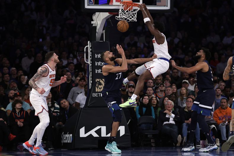 OG Anunoby, de los Knicks de Nueva York, clava el balón sobre la marca defensiva de Rudy Gobert (27), de los Timberwolves de Minnesota, durante la primera mitad del juego de baloncesto de la NBA, el lunes 1 de enero de 2024, en Nueva York. (AP Foto/Adam Hunger)