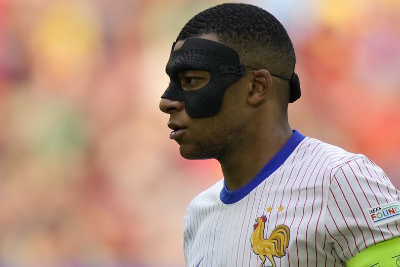 ARCHIVO - Kylian Mbappé de Francia usa una mascarilla durante un partido de octavos de final entre Francia y Bélgica en la Eurocopa 2024 en Düsseldorf, Alemania, el 1 de julio de 2024. El capitán francés ha tenido más máscaras que goles en la Eurocopa 2024. Ampliamente considerado como el heredero de Lionel Messi y Cristiano Ronaldo como el mayor ícono del fútbol, el delantero está luchando con su visión periférica debido a la cubierta protectora que se le ha colocado desde que se rompió la nariz al comienzo de la Eurocopa. (AP Foto/Martin Meissner)
