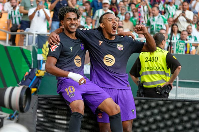 Lamine Yamal (izquierda) celebra con su compañero Jules Koundé tras anotar el primer gol del Barcelona en la victoria ante Real Betis, el sábado 17 de octubre de 2026, en Sevilla. (AP Foto/José Bretón)